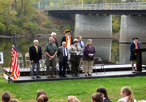 L to R front row: Walloomsac Battle President John Sheaf, Mike McLoughlin, Deputy Supervisor Town of Saratoga, Schuylerville Mayor John Sherman, Saratoga National Historical Park Superintendent Amy Bracewell, Assemblywoman Carrie Woerner back row: Empire State SAR President Duane Booth, Saratoga Battle Chapter SAR President Douglas Gallant, Saratoga Chapter DAR Regent Heather Mabee at podium: Bill Reynolds